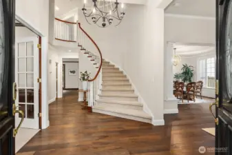 A dramatic, grand curving staircase greets you in the light-filled entry, setting the tone for the home’s elegant interior.