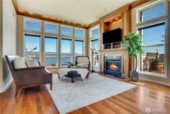 Soaring ceilings, cove lighting in the crown molding, and floor-to-ceiling wood-wrapped windows elevate the living room, making it feel expansive and full of light.