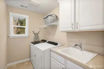 upstairs laundry offers utility sink, storage and linen closet