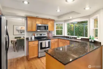 The entertainer’s kitchen is equipped with granite counters, stainless appliances, pull-out shelving, and picture windows looking to peaceful treed views.