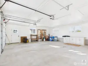 This spacious two-car garage includes a dedicated work area with a built-in work cabinet and windows for natural light.