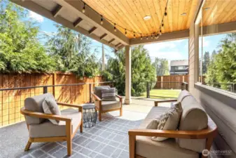 Covered back patio with lights and railings leads to the back yard