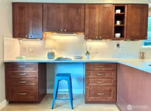 Side work station in the kitchen has pretty tile backsplash and storage.
