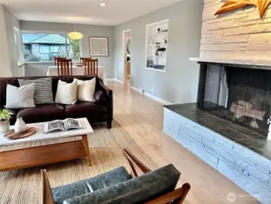 Main floor offers sun-filled living space with wood fireplace & hearth, connection to dining and SE facing oversized windows.