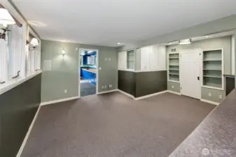 Lower level family room or rec room.  You can see the crafting or planting room in the distance.