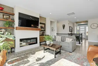 Great room with fireplace and television facing back toward the front door of the home.