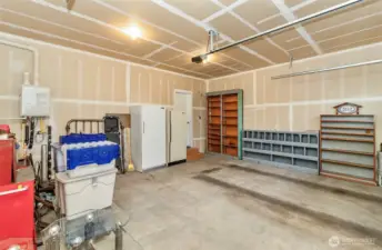 Large 2 car garage. Fridge, freezer and shelving come with the home ( personal items to the left will be removed)  Tankless water heater in garage as well