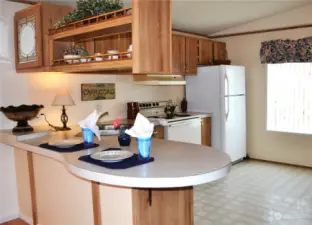 In this view of the kitchen from the entryway, the white stove has been replaced with a stainless steel stove.