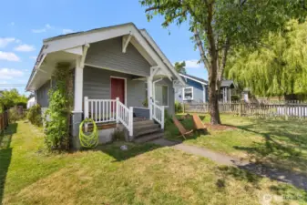 Looking at the front of the home with the large cherry tree and the clematis climbing at the south side of the front porch.