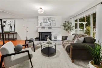 The living room features large windows for letting in lots of light on sunny days and a cozy wood burning fireplace for those rainy winter days