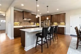 Open-concept kitchen with quartz counters ample cabinetry & stainless appliances.
