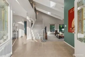 Bright and welcoming entryway with vaulted ceilings, large windows, and an open-concept layout.