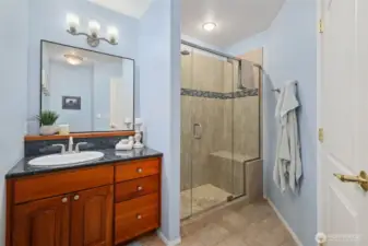 Hall bathroom featuring a wood vanity, modern lighting, and glass-enclosed shower.