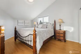 Generous bedroom with vaulted ceiling and warm hardwood flooring. (2)