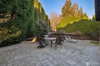 Spacious paved patio with outdoor seating with beautiful mature landscaping.