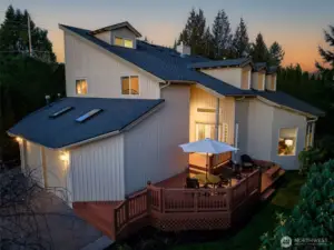 Stunning twilight exterior showcasing the welcoming front deck and warm interior lighting.