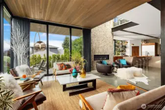 Warm and inviting living room features floor to ceiling windows and cedar lined ceiling. Stacking sliding glass doors open to a view patio