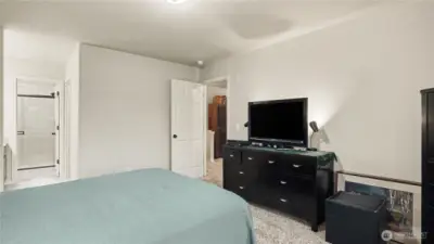Another view of the primary bedroom featuring en-suite bathroom and walk-in closet.