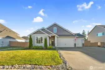 From this angle, the full width of the home and driveway comes into view, offering generous off-street parking and easy access. The manicured lawn and stone accents add to the home’s curb appeal.