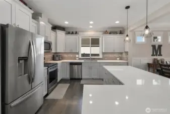 The large island creates a natural gathering spot, with the kitchen opening seamlessly into the dining area and main living space.