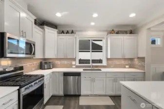 This view highlights the full kitchen workspace, with wraparound counters and a window above the sink that keeps the space feeling light and open.
