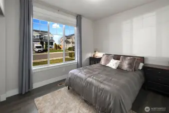Bright bedroom with a large front-facing window, filling the space with natural light and neighborhood views.