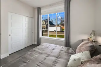 Comfortable bedroom with a large window bringing in natural light and a peaceful neighborhood view.