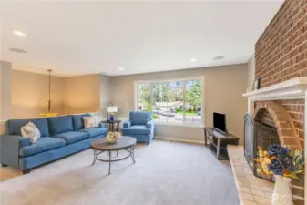 Large open front room with 3 paned window and brick fireplace.