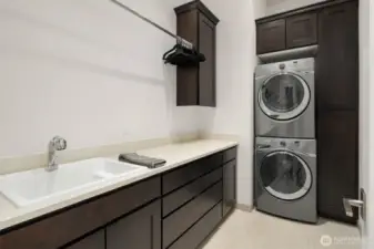 Laundry room with sink cabinets and stacked Whirlpool Duet washer and dryer