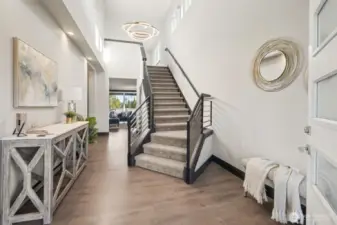 large, welcoming grand foyer, thoughtfully designed, with unique chandelier and open metal staircase.