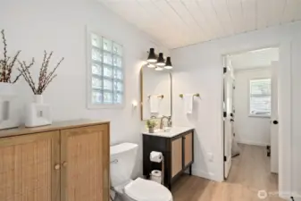 Bathroom connects to all; living/kitchen, primary, guest bedroom/utility room.