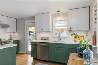 Bright and stylish kitchen featuring two-tone  cabinetry, quartz counters, and modern  finishes with easy access to the backyard.