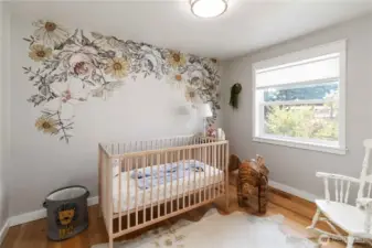 Charming second bedroom with a delightful  floral accent wall, natural light, and versatile  space for your needs.