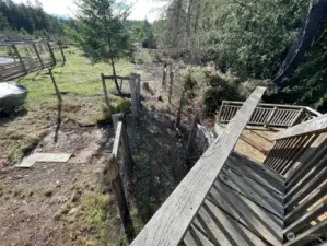 View from top of the bridge to the sundeck. Off to the left is additional fenced in area for the garden, grapevines and greenhouse.
