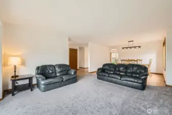 ELEGANT LIVING ROOM WITH GAS FIREPLACE, OPEN FLOOR PLAN, AND ABUNDANT NATURAL LIGHT.