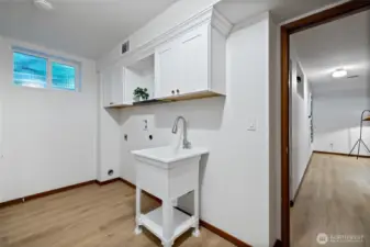 The laundry room has built in cabinets and a utility sink for organization and functionality.