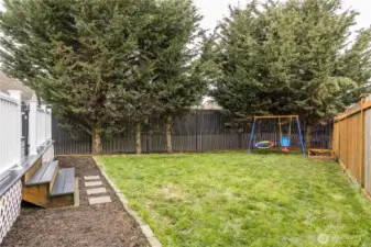 Fully-fenced yard is bordered by mature evergreens for excellent privacy