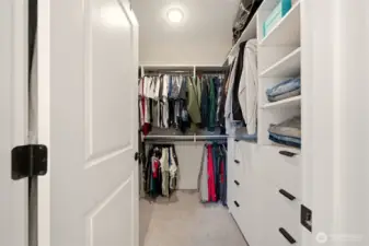 Primary bedroom walk in closet with custom closet system.