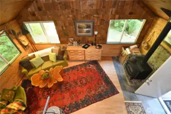 Warmth & charm fill this inviting space, featuring rich wood textures, large windows that frame the outdoors and a cozy wood-burning stove. Unique wood slab table made for the cabin (stays).
