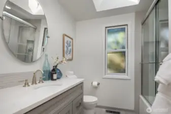 A recently updated main floor full bathroom featuring a sleek modern vanity, contemporary fixtures, and a bright window that keeps the space feeling fresh and airy — a crisp, well-finished retreat serving the adjacent bedroom with style and functionality.