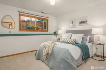 A comfortable and well-appointed lower level bedroom featuring soft neutral tones, plush carpet, and a charming window that brings in natural light — complete with its own ¾ bathroom, making it a quiet, private retreat with excellent potential for a self-contained mother-in-law suite.