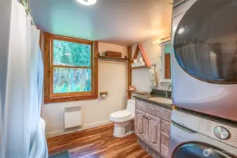 Bathroom featuring a soaking tub, nicely sized window, and a conveniently placed washer and dryer.