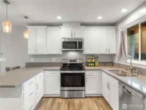 Modern U-shaped kitchen featuring sleek white cabinets, quartz countertops, a peninsula island with seating, and high-end stainless steel appliances—designed for both style and functionality.