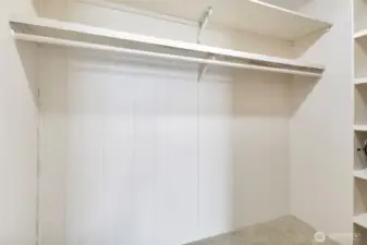 Primary bedroom closet with shelves at the right.