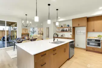 Sleek, modern, and overflowing with storage, the kitchen features stunning slab quartz countertops and backsplash, GE Profile appliances, soft-close cabinetry, and designer lighting.