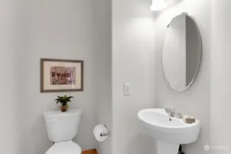 Powder room off entrance, offers a pedestal sink and bamboo flooring