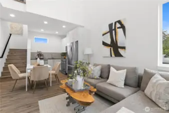 Bathed in light from oversized windows, this open-concept living area is defined by contemporary elegance, highlighted by a striking staircase that adds refinement and sophistication to the space.(Photos are of staged model home.)