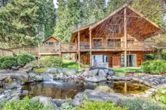 The main house and the studio apartment in the background enjoy stunning views of Puget Sound, mountains, and the man-made waterfall and pond.