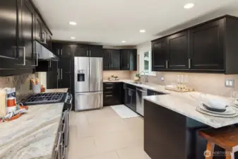 Chef's kitchen with quartzite counters, custom tile backsplash and stainless appliances.