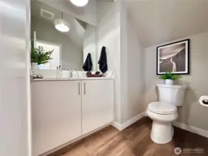 Lovely main floor powder room tucked behind stairwell with under cab lighting and custom light fixture.